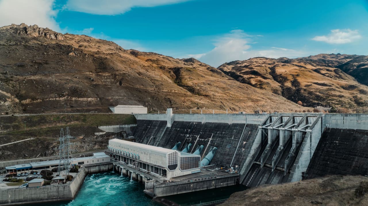 Central hidroelétrica com descarregadores e montanhas ao fundo