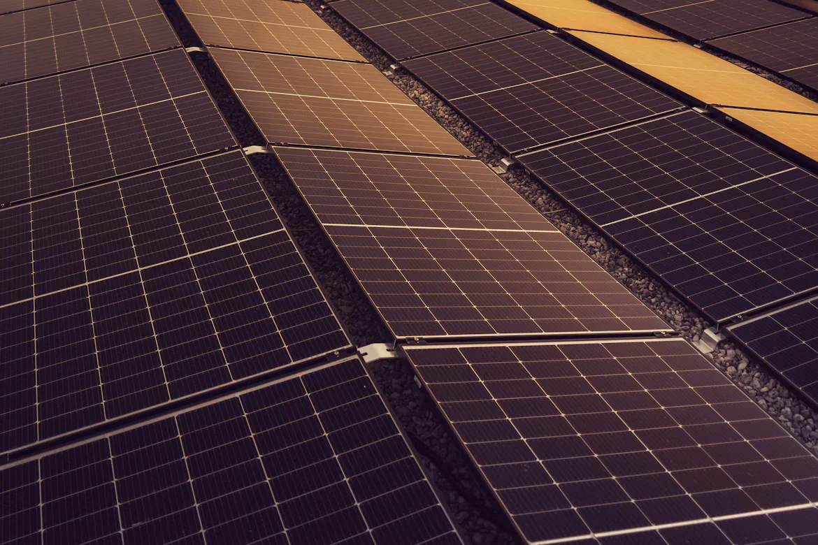 Fila de painéis solares num telhado, ao sol.